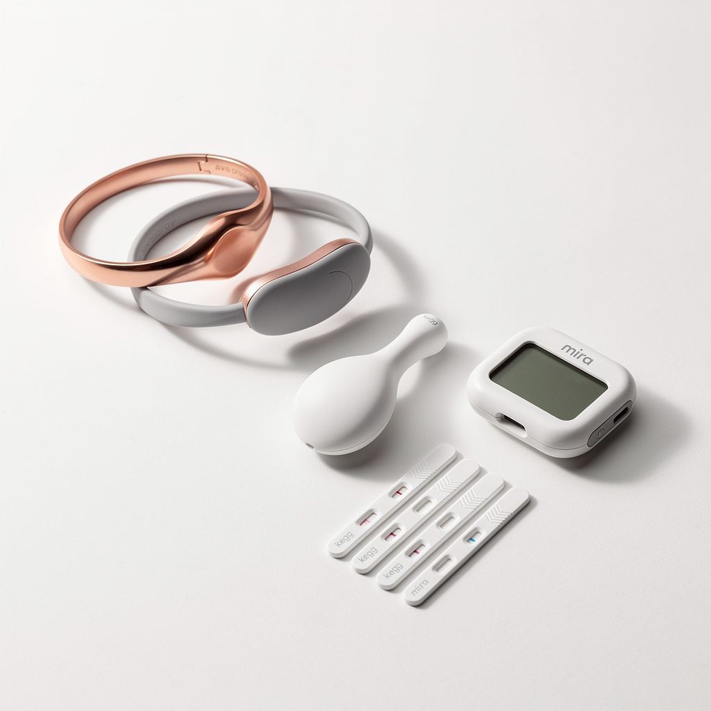 Clean product arrangement of Ava bracelet, Tempdrop armband, Kegg biosensor, and Mira hormone analyzer on white background